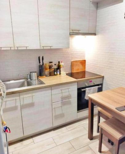 ヴロツワフにあるWyspa apartmentの白いキャビネット、シンク、テーブル付きのキッチンが備わります。