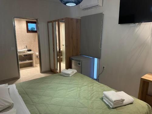 a bedroom with a green bed with towels on it at Sea Side Apartments & Studios-Renovated in Tsilivi
