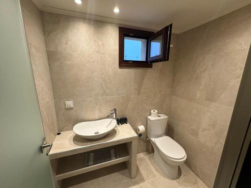 łazienka z toaletą, umywalką i oknem w obiekcie Sea Side Studios w mieście Tsilivi