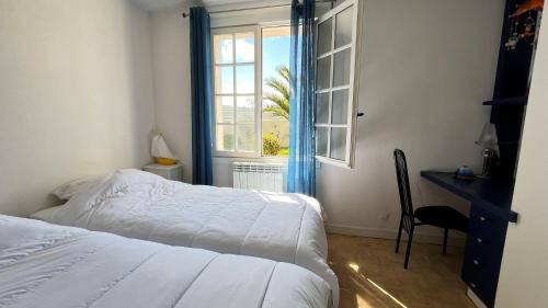 Schlafzimmer mit einem Bett, einem Schreibtisch und einem Fenster in der Unterkunft Maison le Vent du Large in Sibiril