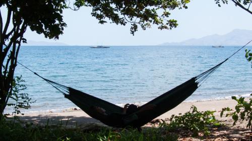 a person laying in a hammock on the beach at Sunset Cottages in Hitokalak