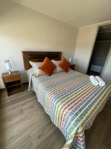 a bedroom with a large bed with orange pillows at Departamento Tucapel 2 centro de Concepción in Concepción