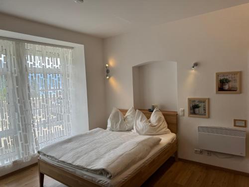 a bedroom with a bed with white sheets and a window at Seepanorama an der Esplanade 2 in Gmunden