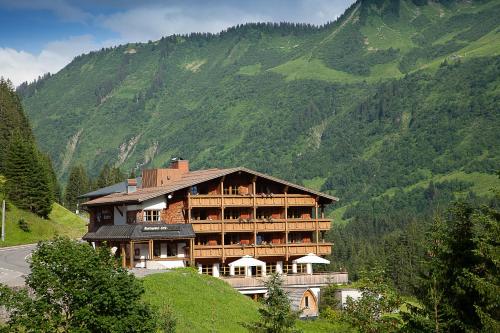 a large building on a hill with a mountain at Alpine Lifestyle Berghotel Madlener in Damuls