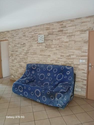 - un canapé bleu dans une chambre avec un mur en briques dans l'établissement CHAMBRE A LOUER Marseille, à Marseille