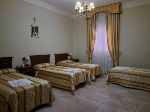 een kamer met 3 bedden en een kroonluchter bij casapaceebene in San Giovanni Rotondo