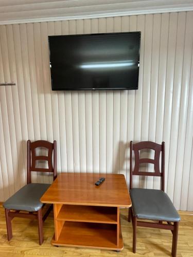 a table and two chairs with a television on a wall at Gintagnė in Aleksandrija