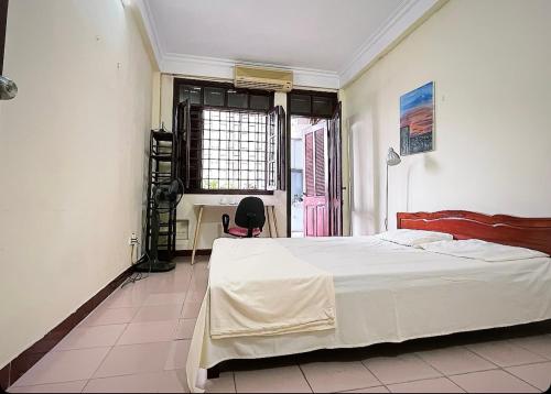 a bedroom with a bed and a desk and a window at Tropical land little Hanoi homestay in Hanoi