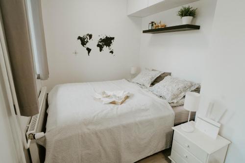 1 dormitorio con 1 cama blanca y un mapa mundial en la pared en ~ A modern flat at a calm ground floor ~ en Espoo