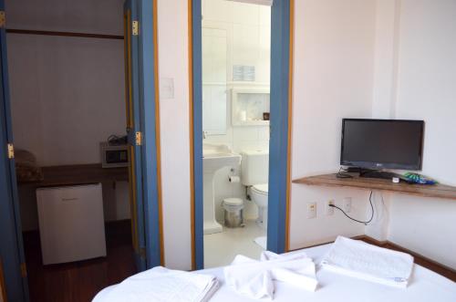 a room with a bathroom with a toilet and a television at Hotel Solar de Maria in Ouro Preto