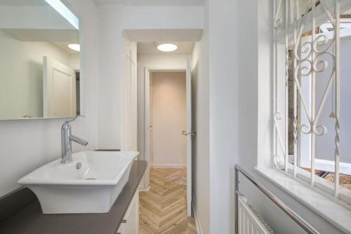 ein weißes Bad mit einem Waschbecken und einem Fenster in der Unterkunft Charming studio in London