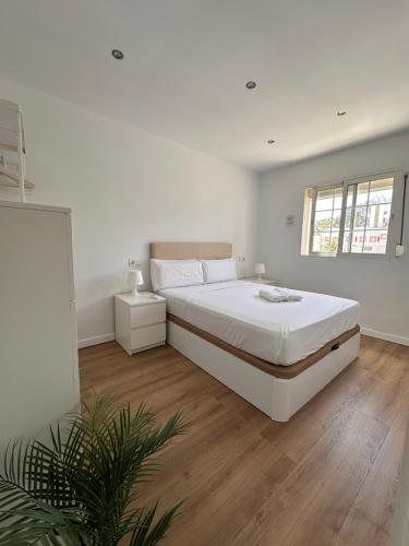 Claveles de Luxe في مالقة: غرفة نوم بيضاء بسرير كبير وارضية خشبية