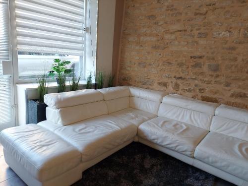 a white couch in a living room with a brick wall at Appartement Jarnioux - Les Meublés des Pierres Dorées in Theizé