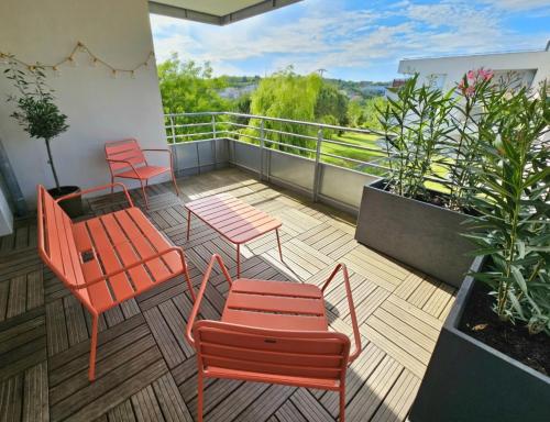 un balcón con sillas naranjas, mesas y plantas en Superbe Apt 2 ch, terrasse, WIFI, parking gratuit, en Toulouse