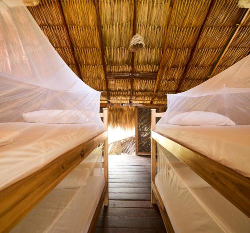 two beds in a room with a thatched roof at Bungalows Casa Rio Palomino in Palomino
