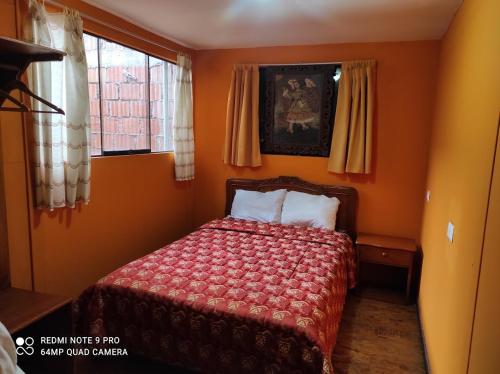a bedroom with a bed with orange walls and windows at Welcome Cusco Hostel in Cusco
