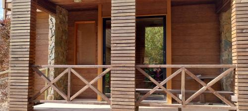 a front porch of a house with a wooden railing at Cabañas Rancho Pinares in Pichilemu