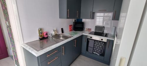 a small kitchen with blue cabinets and a sink at The Hideaway ll private garden Quiet Central in Southport
