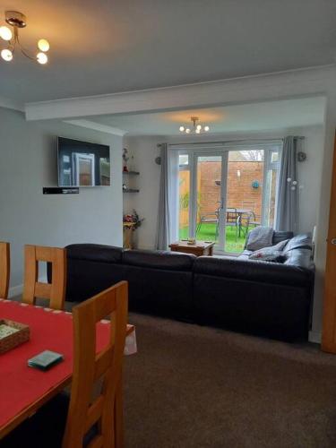 a living room with a black couch and a table at Modernised home with 2 bedrooms in Cardiff in Cardiff
