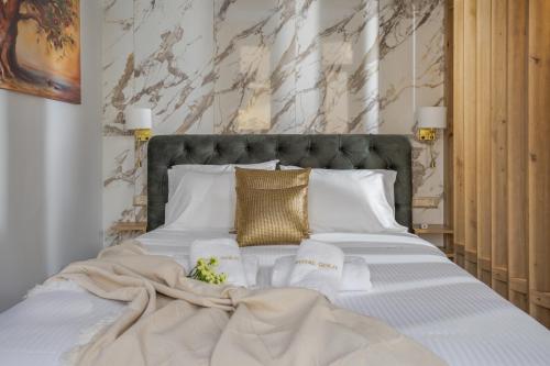 uma cama grande com lençóis brancos e almofadas douradas em Royal Gold City Suites by Estia em Iráclio