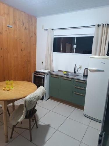 a kitchen with a table and a refrigerator and a sink at Pousada Tertulia Apartamento completo em Lages! in Lages