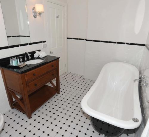 a white bathroom with a tub and a sink at The Yarrawonga Hotel in Yarrawonga