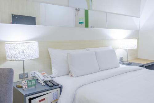 ein Schlafzimmer mit einem Bett und einem Telefon auf einem Nachttisch in der Unterkunft Go Hotels Lanang - Davao in Davao City