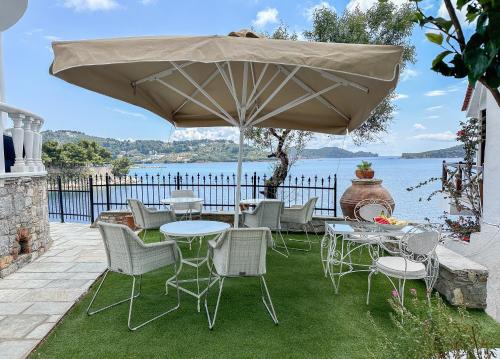 a patio with tables and chairs under an umbrella at ClubOrsa Ourania's Mansion in Skiathos