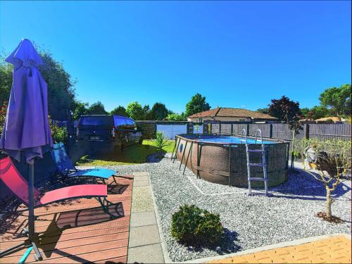 une cour arrière avec une piscine, un parasol et une aire de jeux dans l'établissement MAISON PISCINE PRIVEE 4a5 PERS9 & 11 KMs DES PLAGES OCEANES ET DU LAC, à Linxe