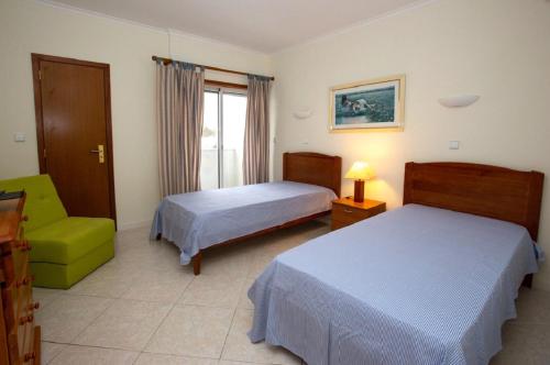 a hotel room with two beds and a green chair at Onda Verde in Albufeira
