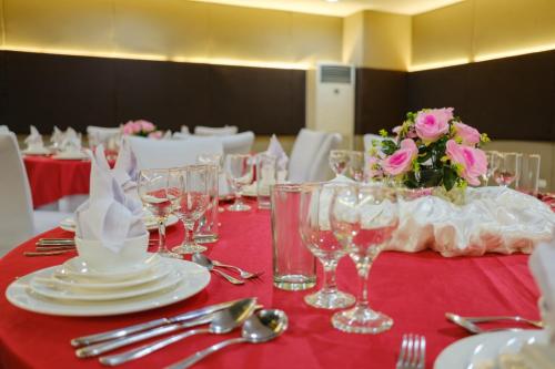 a table with a red table cloth with glasses and flowers at Go Hotels Lanang - Davao in Davao City