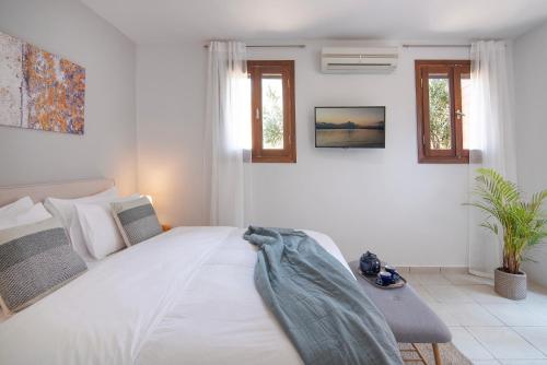 a white bedroom with a large white bed and windows at PYRGOS RALLI ESTATE Guesthouse in Aegina Town