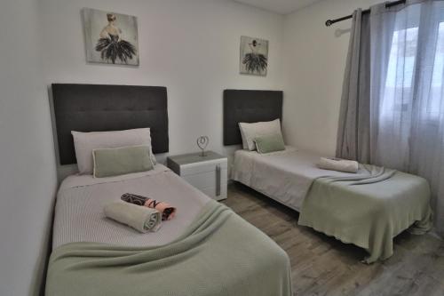 ein Schlafzimmer mit zwei Betten und einem Fenster in der Unterkunft Vila Castro in Estreito da Calheta