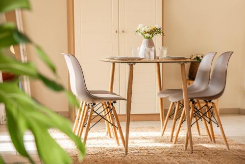 a table with three chairs and a table with flowers on it at PYRGOS RALLI ESTATE Guesthouse in Aegina Town