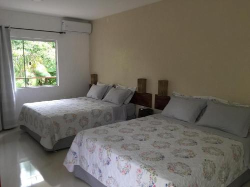 um quarto com 2 camas e uma janela em Pousada das Palmeiras em Salinópolis