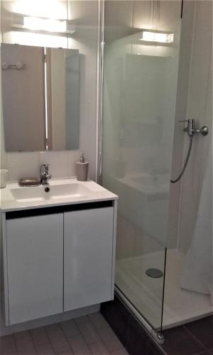une salle de bain blanche avec un lavabo et une douche dans l'établissement appartement vue mer piscines parking LES CORAUX AGAY PLAGE, à Agay