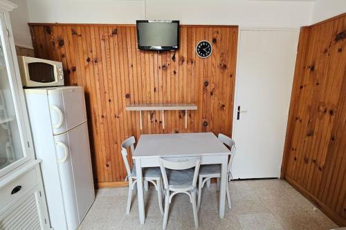 une cuisine avec une table et des chaises blanches ainsi qu'une télévision dans l'établissement Appartement Le Muy, au Muy
