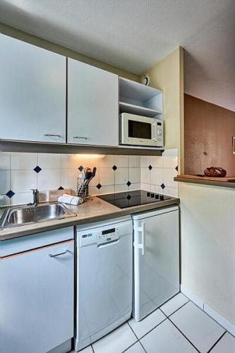une cuisine avec un évier et un micro-ondes dans l'établissement Résidence Port Guillaume - maeva Home - Appartement 3 pièces 6 personnes - Budget MAE-9231, à Dives-sur-Mer