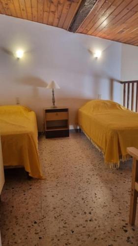 deux lits dans une chambre avec des draps jaunes dans l'établissement Appartement familial région PACA, au Muy