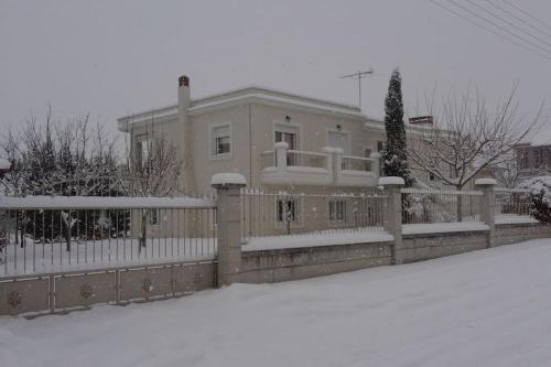 a house with a fence in the snow at Vintage Garden House in Doxato