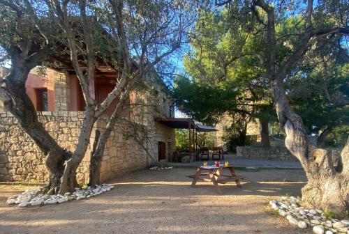 a wooden bench in front of a stone building with trees at PYRGOS RALLI ESTATE Guesthouse in Aegina Town