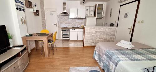 a room with a bed and a table and a kitchen at Rooms & studio OLD TOWN PAG in Pag