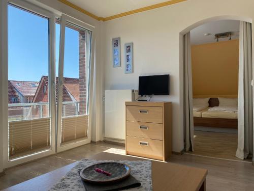 uma sala de estar com televisão e um quarto com varanda em Haus Kap Horn em Juist