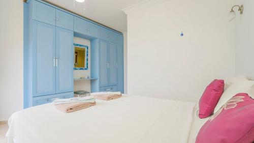 a bedroom with blue cabinets and a white bed with pink pillows at Villa Panorama, Kalkan, Private Pool, Panoramic Sea View in Kalkan