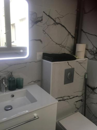 une salle de bain blanche avec un lavabo et un miroir dans l'établissement Appartement paris Tour Eiffel, à Paris