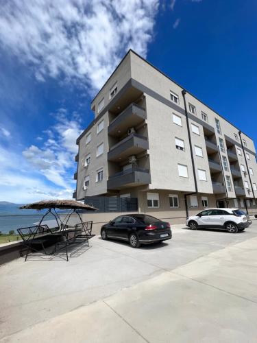 two cars parked in a parking lot in front of a building at Lakeview Appartment Kalina in Star Dojran
