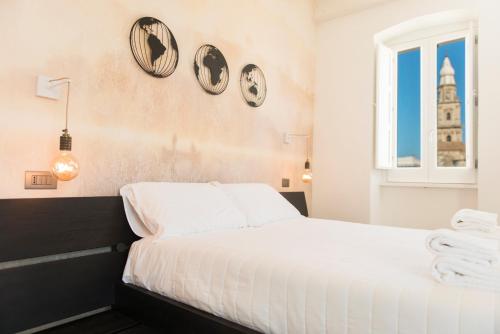 a bedroom with a white bed with clocks on the wall at Monsignore Maisons in Monopoli