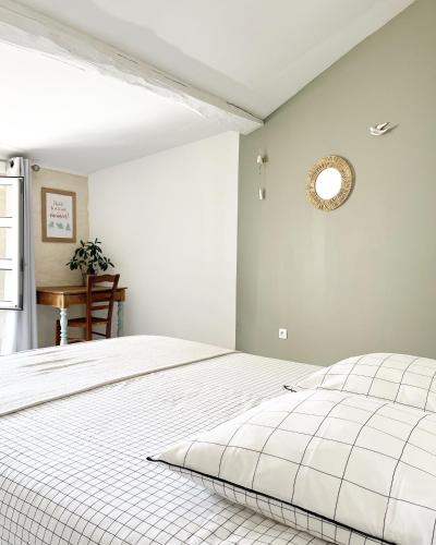 - une chambre avec un lit blanc et une horloge murale dans l'établissement Le 19 Rue **,Maison de charme proche du Puy du Fou, à Mouchamps