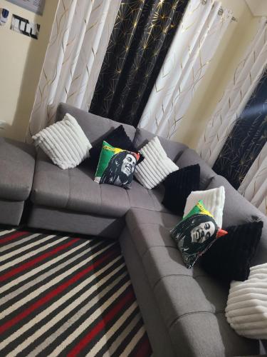a grey couch with pillows on top of it at The Surada Bay in Old Harbour