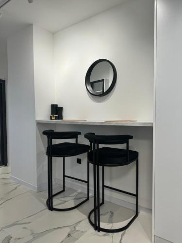 a vanity with two black stools and a mirror at Apartman Bor in Sokolac
